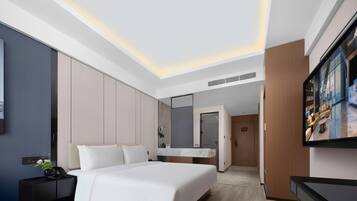 Una habitación de hotel moderna con una cama grande, una mesita de noche, un televisor y un armario.