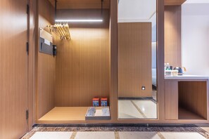 Habitación de hotel con paneles de madera, un espejo, una mesita con artículos de aseo y un banco con una toalla.