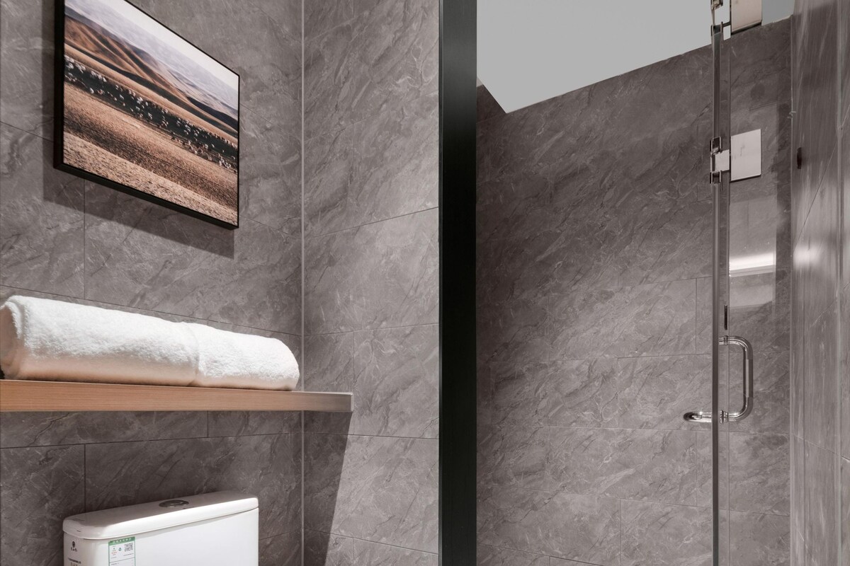 A modern bathroom with a toilet, a shower, and a mounted picture.