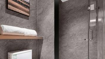 Un baño moderno con inodoro, ducha y un cuadro colgado.