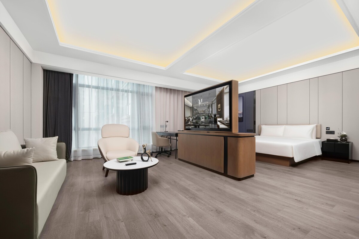 Une chambre d’hôtel moderne avec un canapé, une table basse ronde, un téléviseur et un lit.