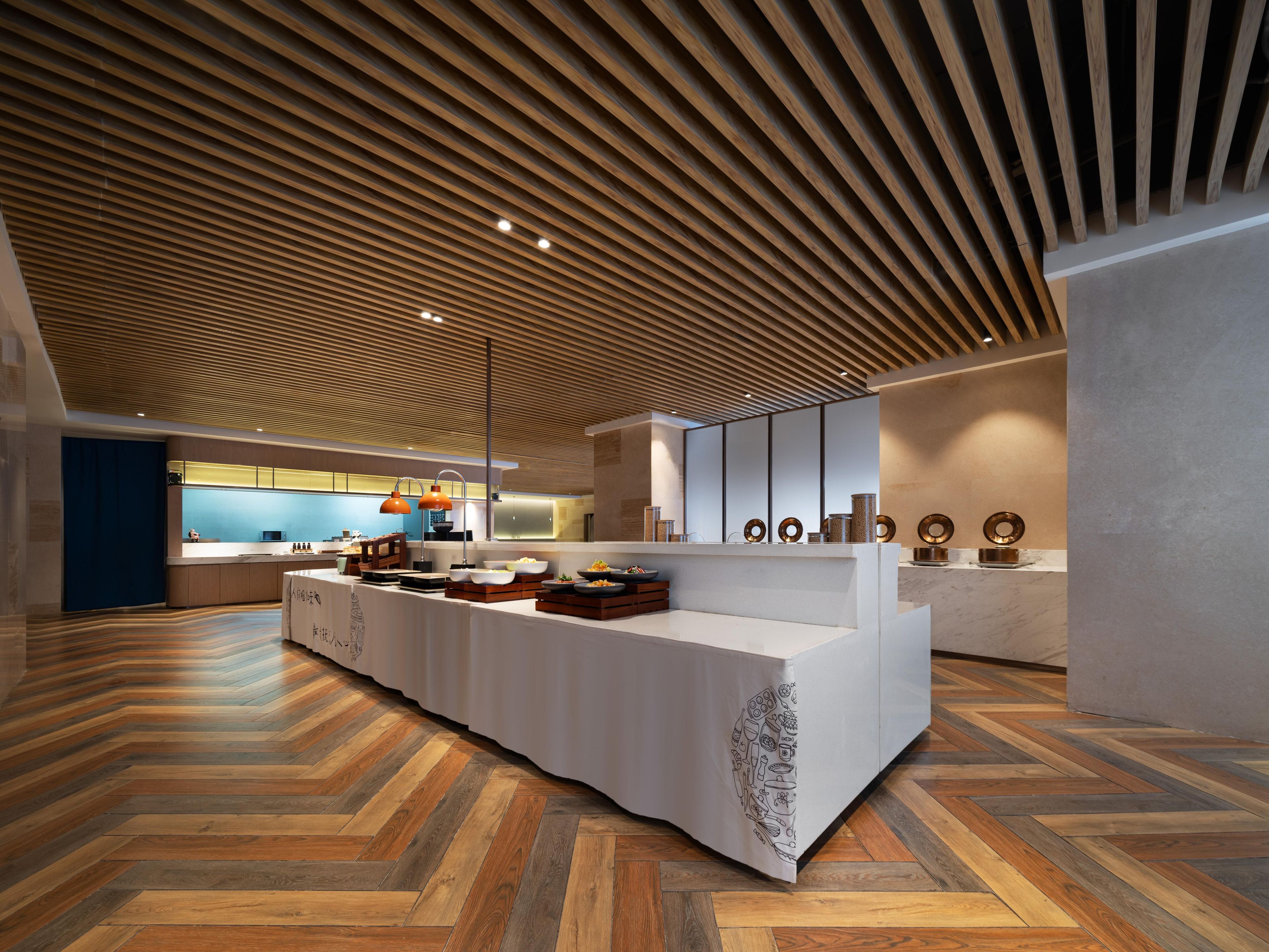 Cozinha moderna com bancada comprida, teto de madeira e padrão de piso em herringbone.