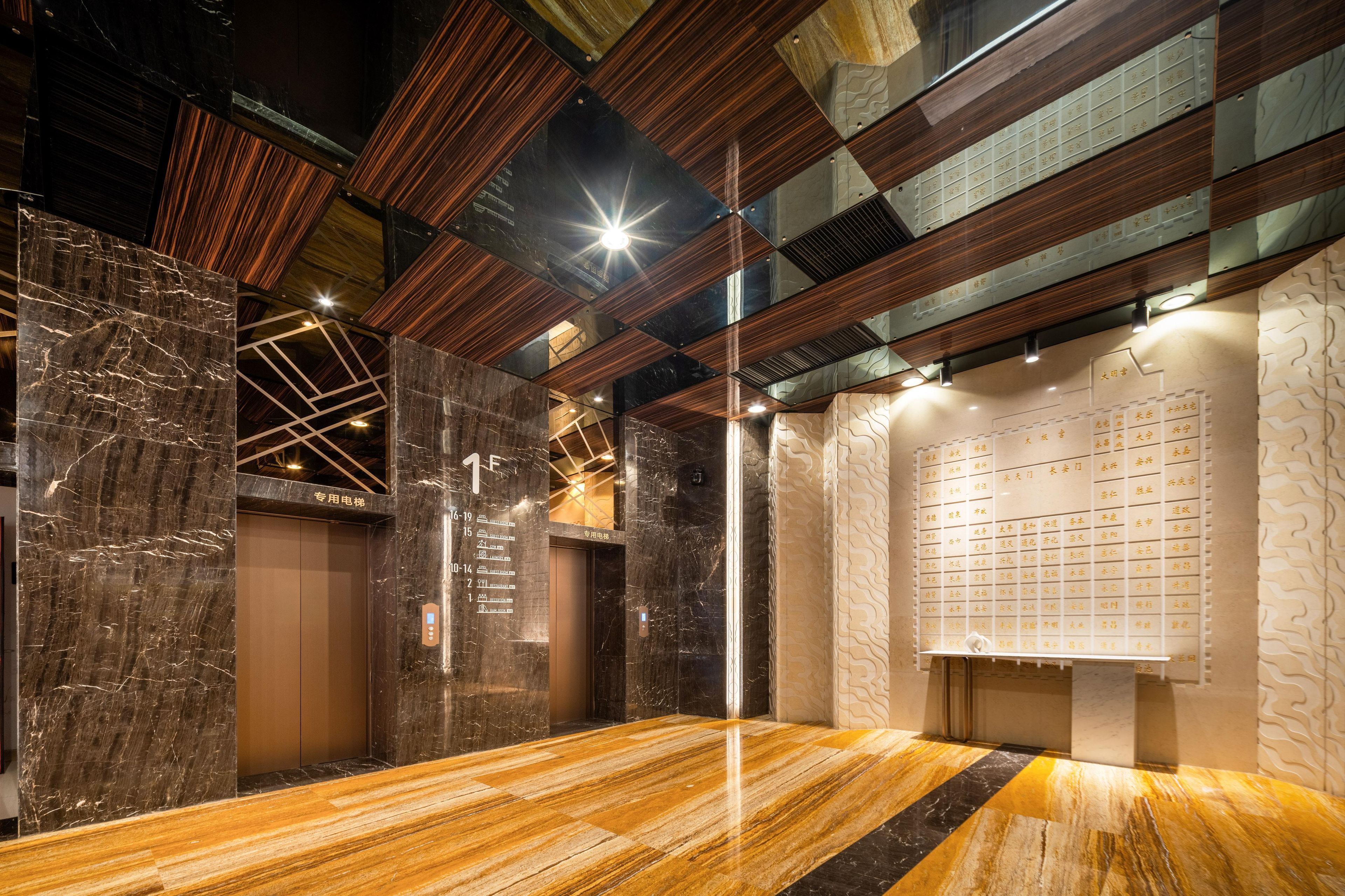 A modern elevator interior with marble walls, wooden paneling, and a digital display.