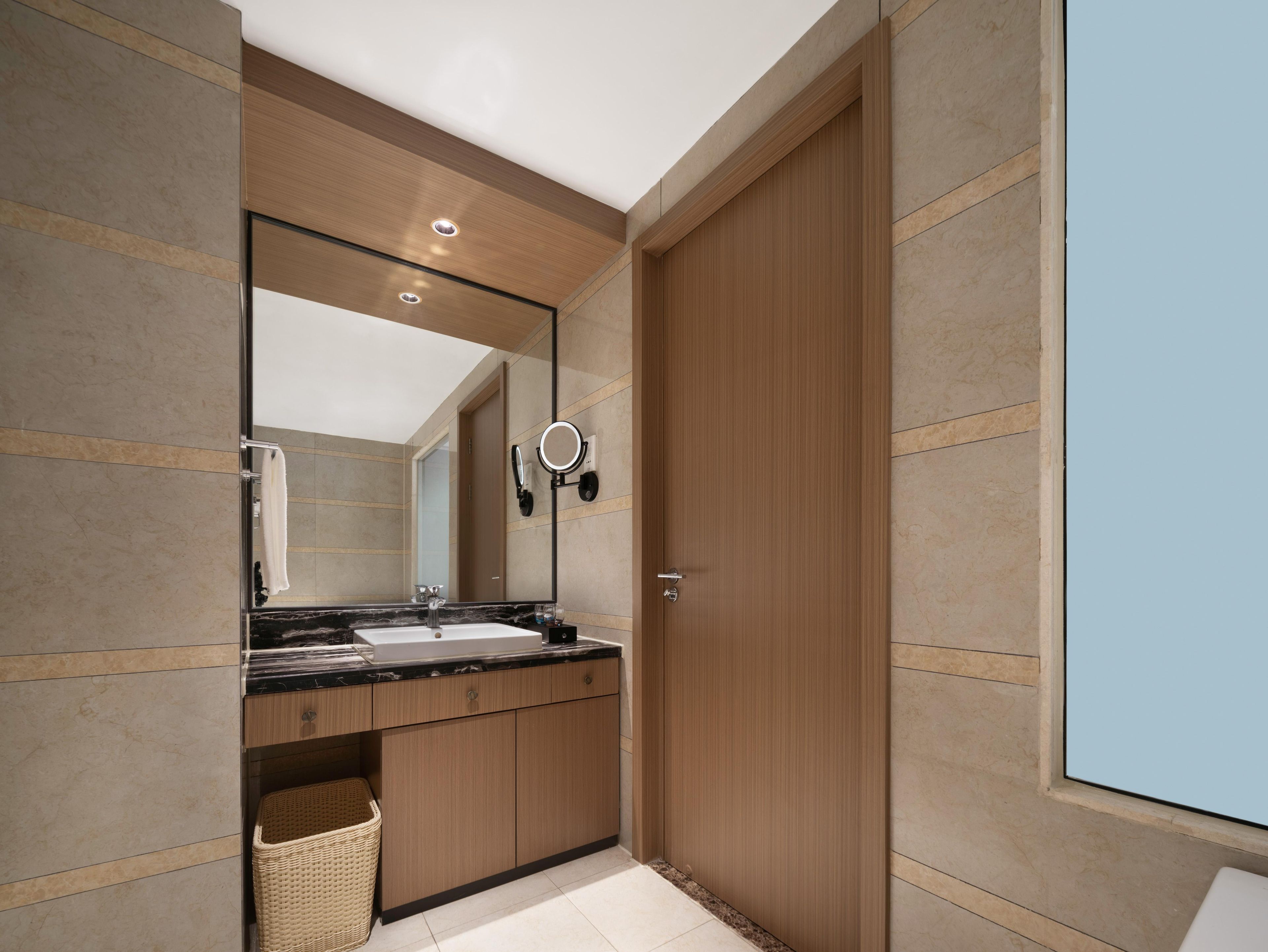 A modern bathroom with a wooden vanity, a large mirror, and a built-in sink.