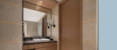 A modern bathroom with a wooden vanity, a large mirror, and a built-in sink.