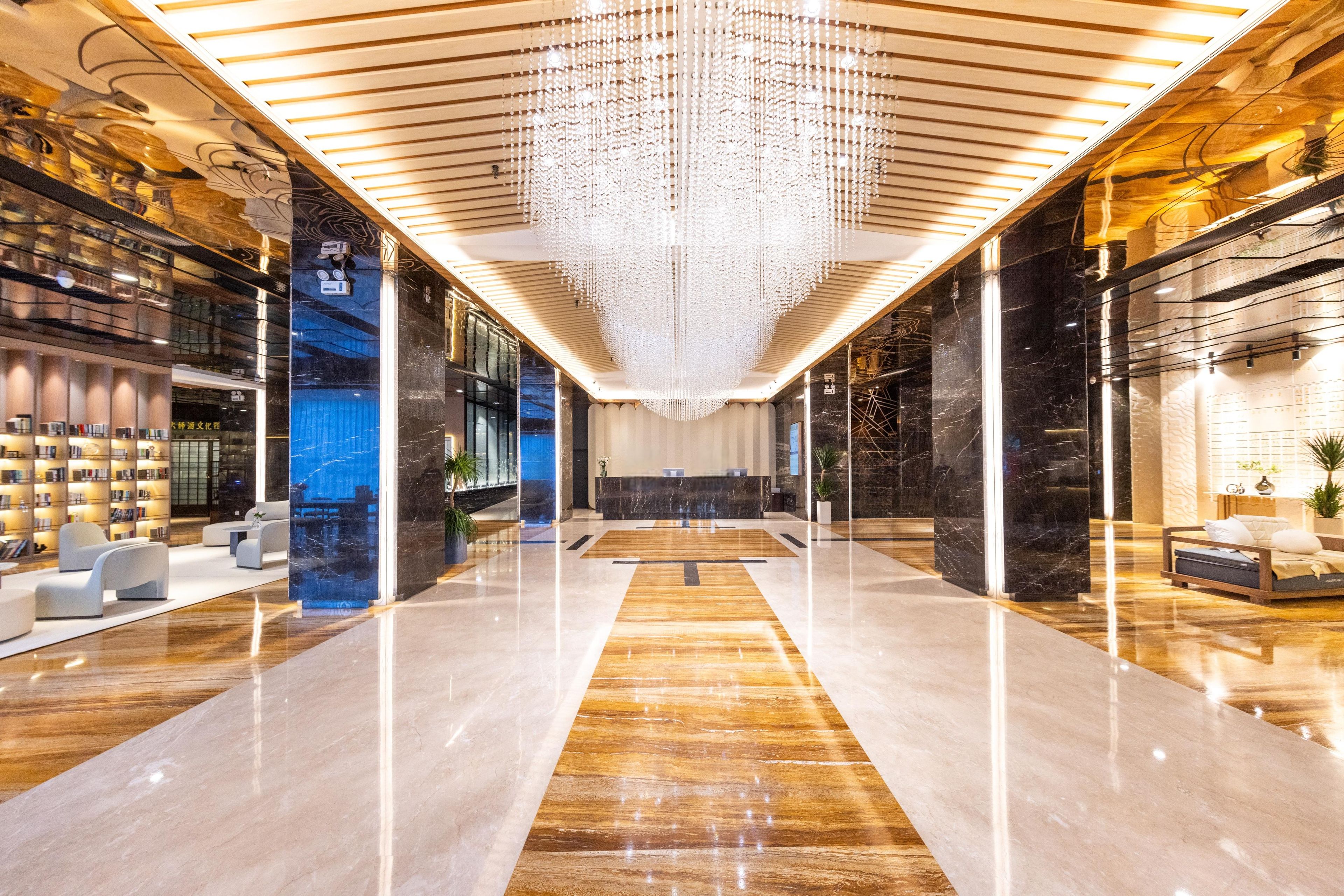 Un vestíbulo espacioso con un mostrador de recepción central, zonas de estar modernas y un candelabro decorativo.
