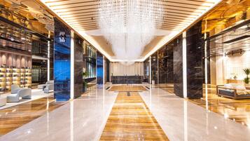 Un vestíbulo espacioso con un mostrador de recepción central, zonas de estar modernas y un candelabro decorativo.