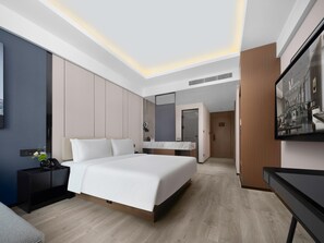 Une chambre d’hôtel moderne avec un grand lit, une table de chevet, un miroir et un téléviseur.