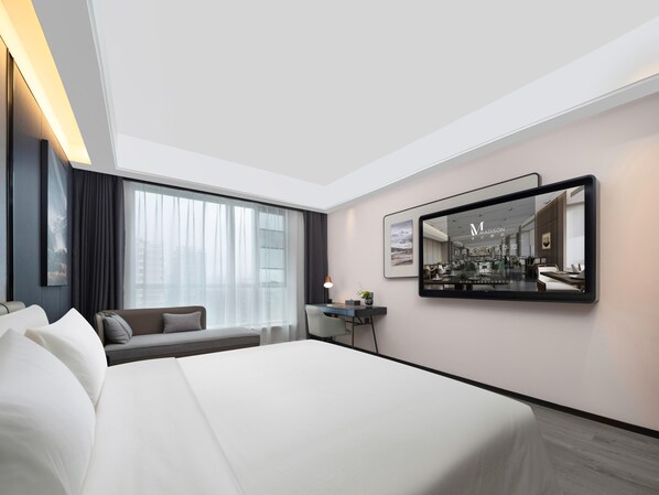 A hotel room with a large bed, a desk, a chair, a sofa, and a large mirror on the wall. - Meilun Hotel Xian Qujiang Convention Center Mixc (Xi'an)