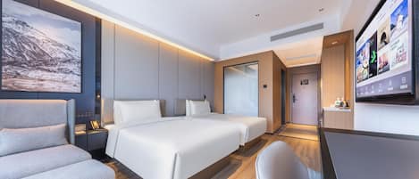 A modern hotel room with a large bed, a sofa, a desk, and a TV.