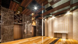 Een modern liftinterieur met marmeren wanden, houten lambrisering en een digitaal display.