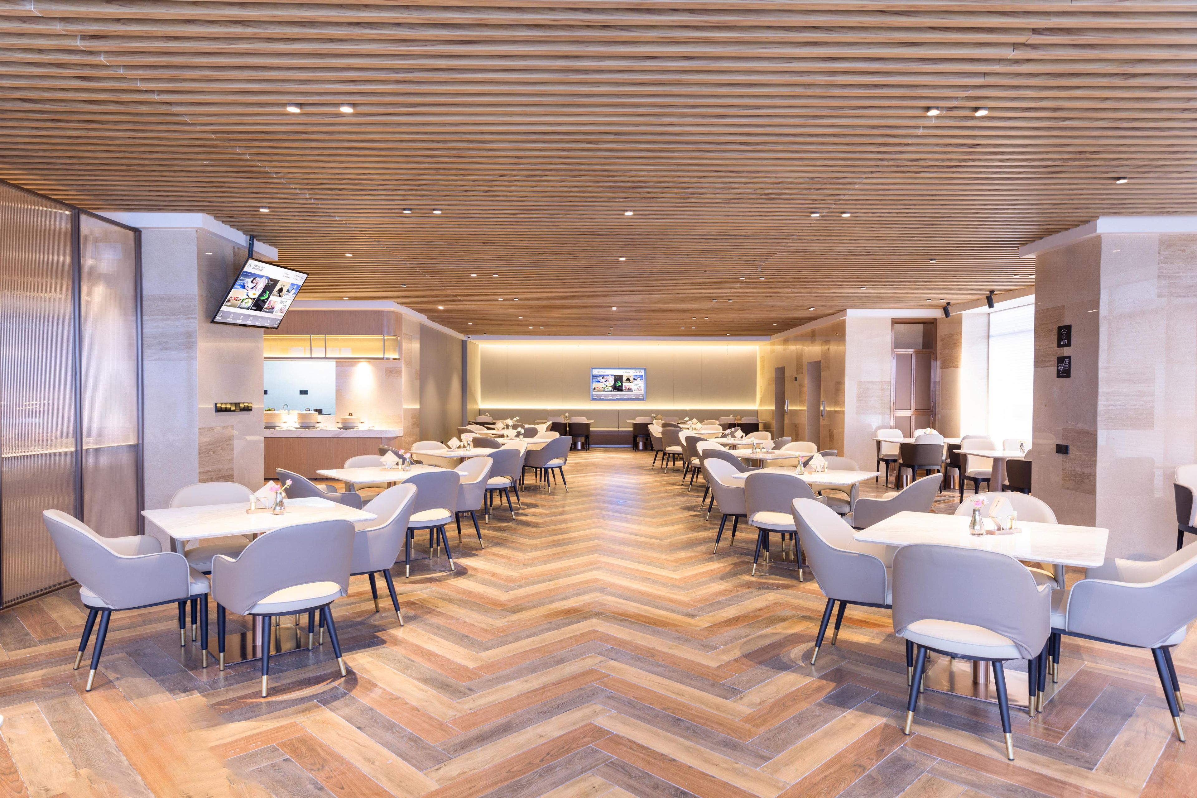 A spacious dining area with multiple tables and chairs, a wooden ceiling, and a modern interior design.