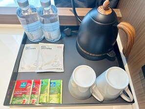 Una bandeja amb una papereta, dues tasses, aigua embotellada, sobres de cafè i sobres de te.