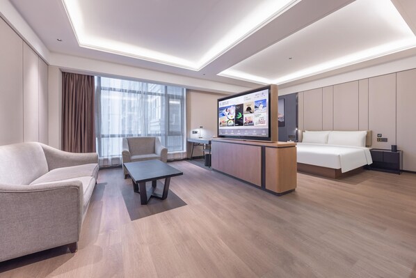 A modern hotel room with a sofa, a coffee table, a TV, a bed, and a desk with a computer. - Meilun Hotel Xian Qujiang Convention Center Mixc (Xi'an)