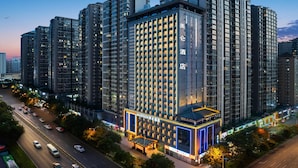 Een hoog hotelgebouw met meerdere verdiepingen, een opvallende ingang en een goed verlichte gevel.