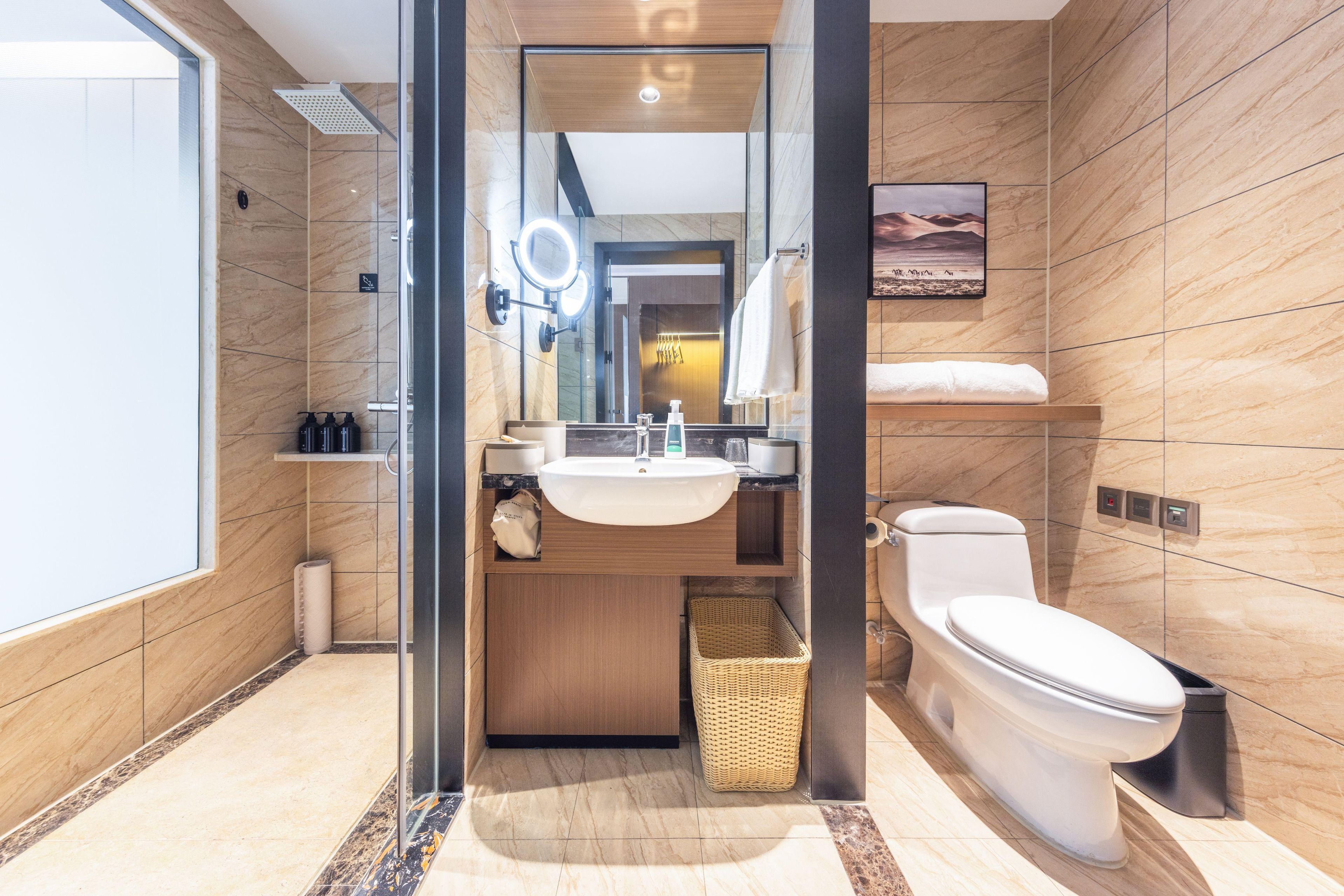 A modern bathroom with a glass-enclosed shower, a sink with a mirror, a toilet, and a small shelf with toiletries.