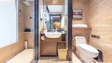 A modern bathroom with a glass-enclosed shower, a sink with a mirror, a toilet, and a small shelf with toiletries.