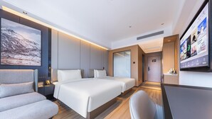Een moderne hotelkamer met een groot bed, een sofa, een bureau en een televisie.