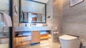 A modern bathroom with a large mirror, a white toilet, and a vanity with a sink and towel rack. - Grand Madison Hotel Quzhou High-speed Railway Sta (Quzhou)