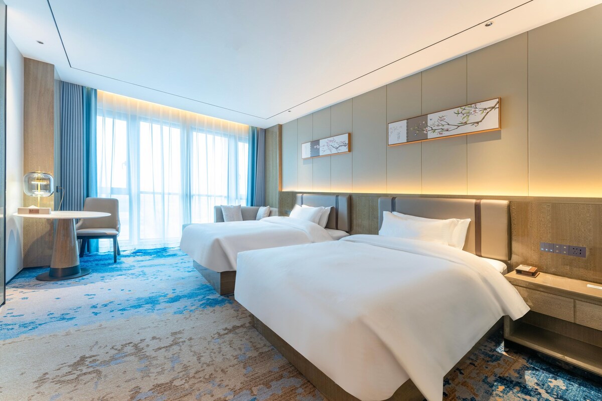 Een hotelkamer met twee bedden, een bureau en een stoel.