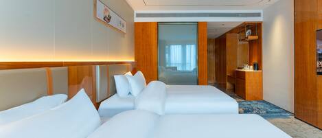 A hotel room with two beds, a wooden headboard, a desk with a chair, and a large mirror.