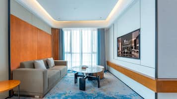 Una habitación de hotel moderna con sofá, una mesa redonda y un ventanal grande.