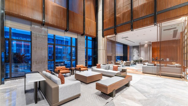 A spacious lobby with modern furniture, large windows, and a high ceiling.