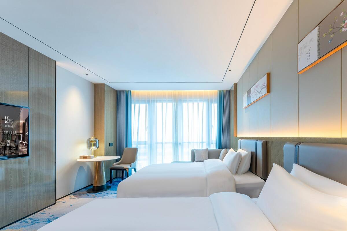 Ein Hotelzimmer mit zwei Betten, einem Schreibtisch und einem Stuhl.