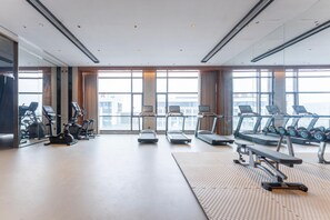Une salle de sport moderne équipée de tapis de course, de vélos elliptiques et de poids libres.
