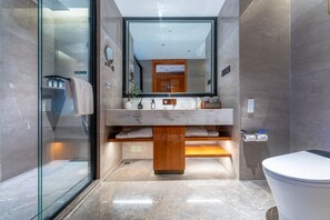 Een moderne badkamer met een glazen douchecabine, een marmeren wastafelmeubel en een grote spiegel.