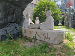Une sculpture en pierre représentant trois personnages assis sur un rocher, avec des inscriptions.