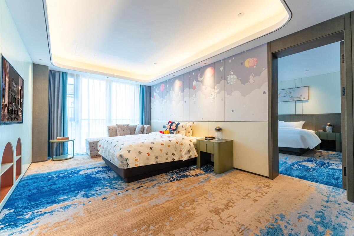 Ein modernes Hotelzimmer mit einem großen Bett, einem Nachttisch, einem kleinen Tisch und einem großen Fenster.