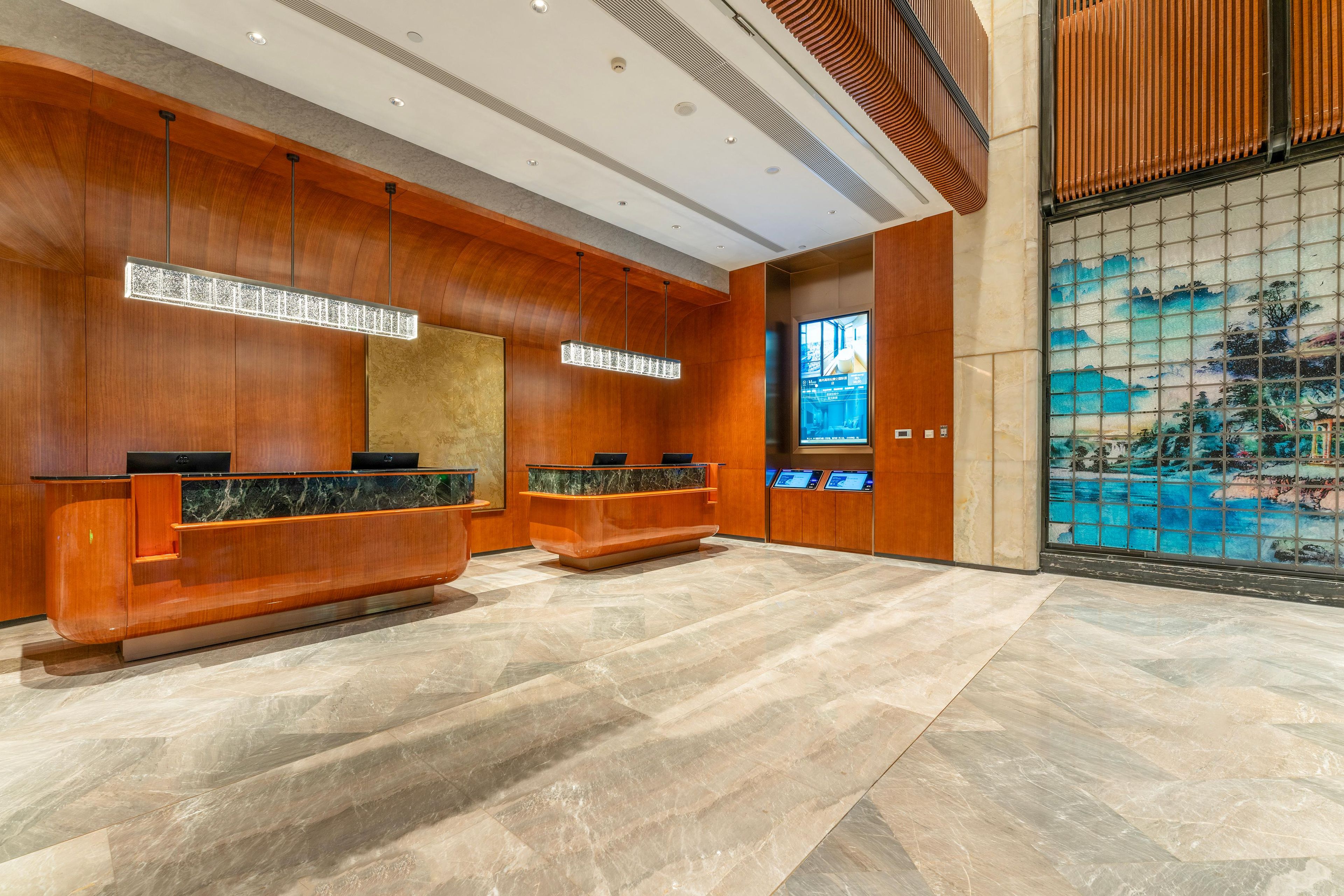A reception area with wooden paneling, marble countertops, and a large digital display.