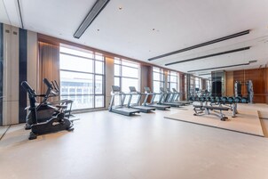 Un gimnasio moderno con cintas de correr, elípticas y pesas libres.