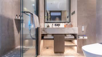 Un baño moderno con cabina de ducha de vidrio, lavamanos de mármol y un inodoro.