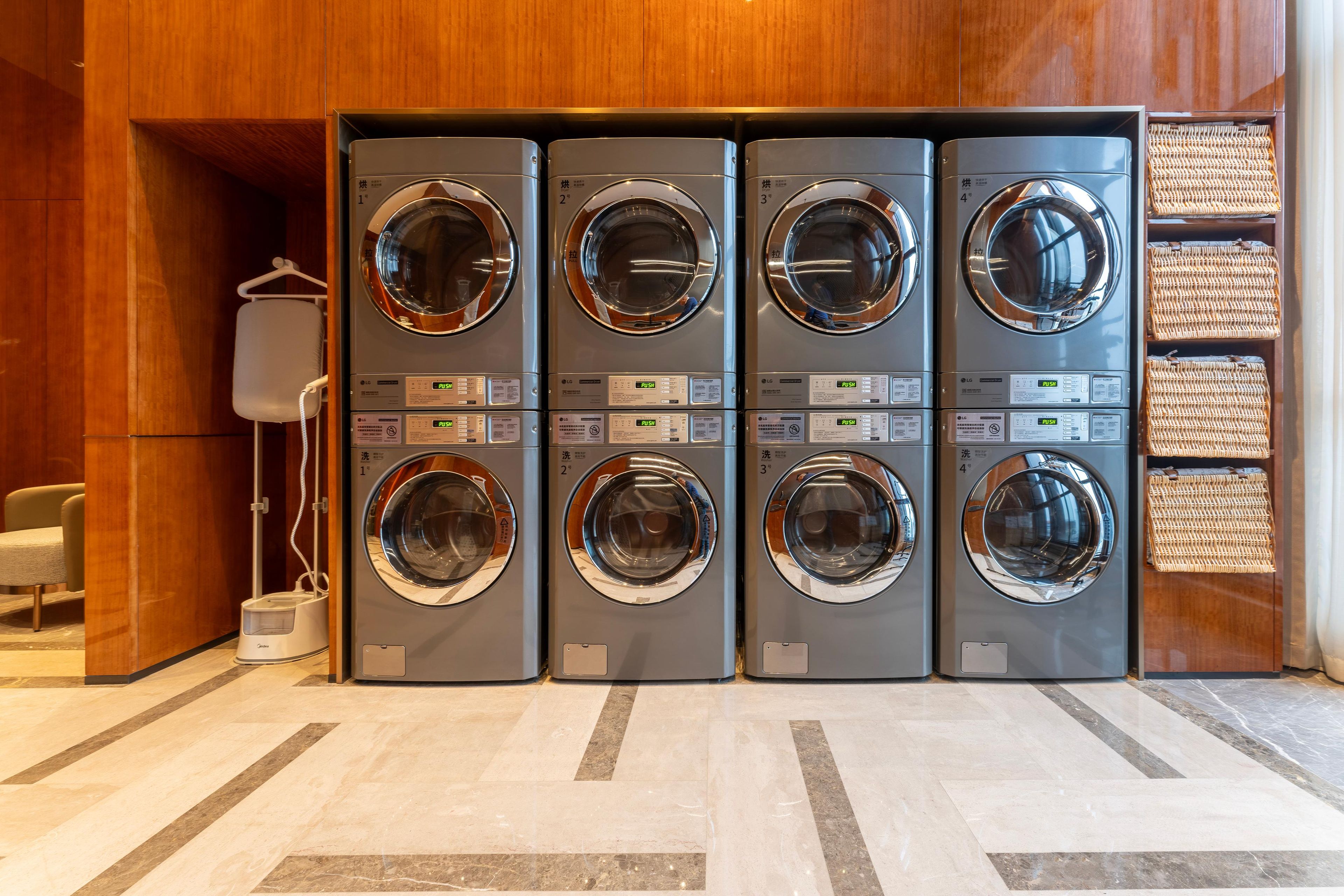 A row of four front-loading washing machines in a commercial setting.