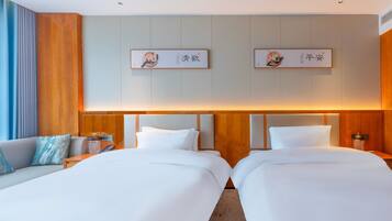 A hotel room with two beds, a sofa, and a nightstand with a lamp.