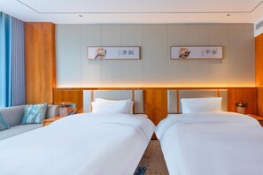 A hotel room with two beds, a sofa, and a nightstand with a lamp. - Grand Madison Hotel Quzhou High-speed Railway Sta (Quzhou)