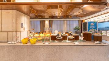 A buffet setup with various food items and bowls on a marble counter.