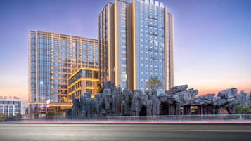 Un hotel moderno con varios edificios de gran altura, que destaca por su entrada con una formación rocosa y una fachada bien iluminada.
