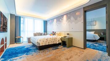 A modern hotel room with a large bed, a nightstand, a small table, and a large window.