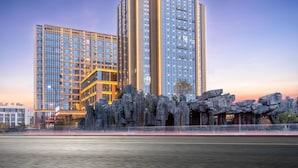 A modern hotel with multiple high-rise buildings, featuring a prominent entrance with a rock formation and a well-lit facade.