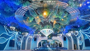 A spacious indoor venue with a central stage, surrounded by seating and decorative lighting.