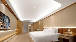 A modern hotel room with a large bed, bedside tables, a nightstand, and a large window.
