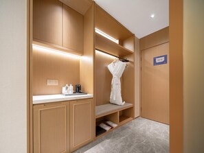 Habitación de hotel con tocador de madera, bata colgada en un perchero y un cartel con el número de la habitación.