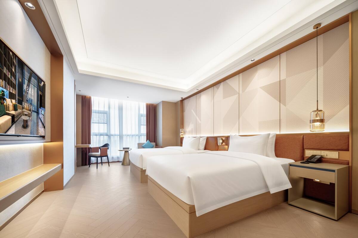 Habitación de hotel moderna con una cama grande, un escritorio y una zona de estar con vistas a la ciudad.