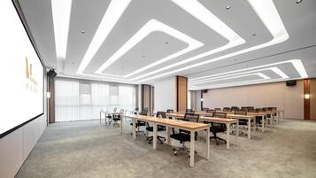 Una sala de conferencias moderna con una mesa larga, sillas y una pantalla de proyector.