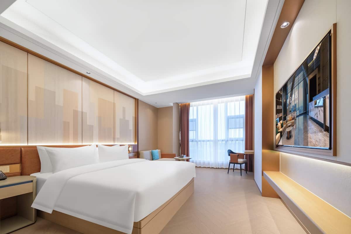Una habitación de hotel moderna con una cama grande, un escritorio y un área de descanso.