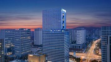 A high-rise hotel with a modern glass facade, multiple floors, and a prominent signage at the top.