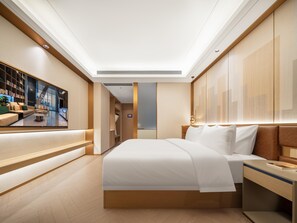 A modern hotel room with a large bed, a bedside table, a nightstand, a seating area with a sofa and a coffee table, and a large window with a view of the city. - Madison Hotel Wuxi Luocheng (Wuxi)